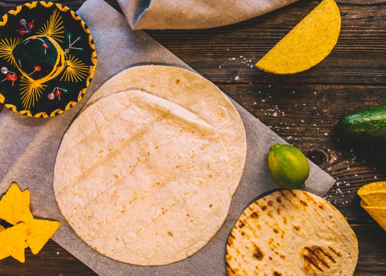 tortilla-mexicana-trigo-sabrosos-nachos-limones-mesa-madera-sombrero-mexicano (1)